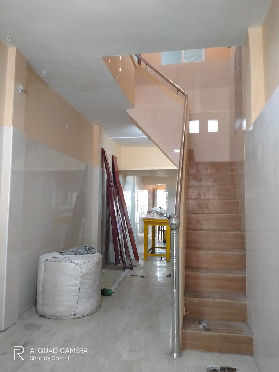Kavery Metal staircase renovation at finishing stage — wooden-finish tile steps, stainless steel railing and painted walls by Jayam Construction, Kumbakonam