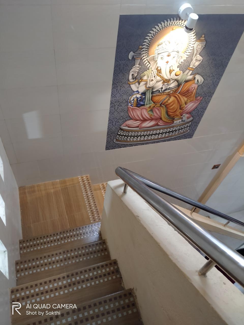 Kavery Metal renovation — Ganesha ceiling mural tile with spotlight above tiled staircase and SS railing, Sarangapani Street, Kumbakonam